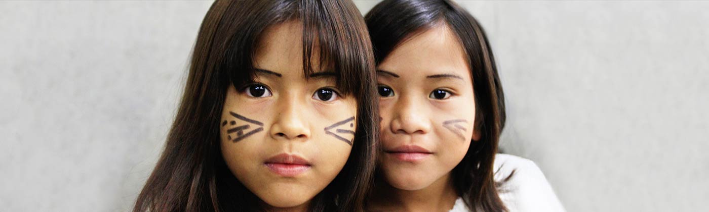 Imagem com o rosto de duas crianças da comunidade indígena