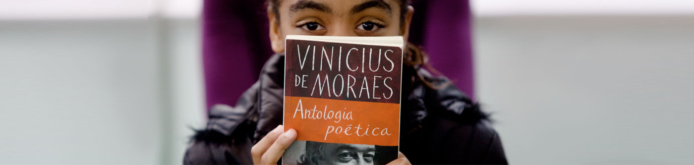 Imagem de um menino segurando o Livro 'Antologia Poética', de Vinícius de Moraes, na frente do rosto