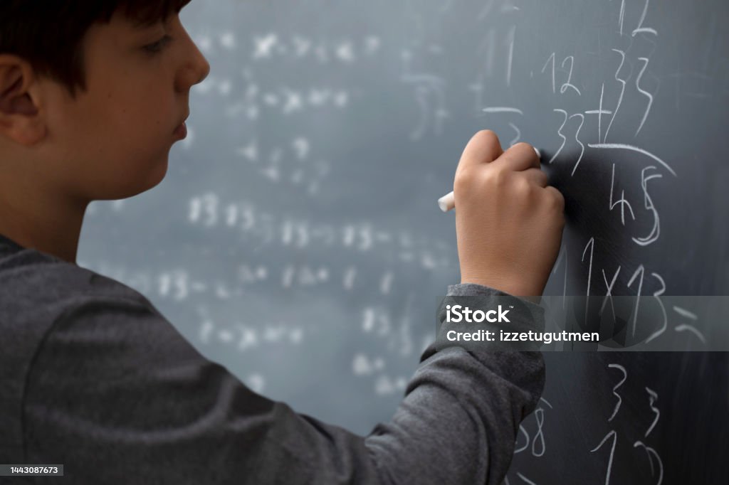 student kid writing to the blackboard at school